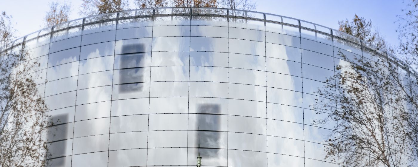 A curved modern glass facade reflecting the sky